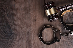 handcuffs and judge gavel on wooden background