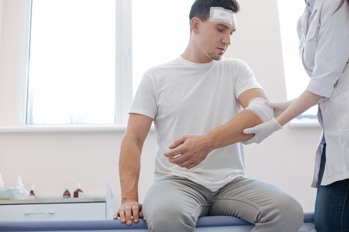 Cheerless wounded man looking at his injury