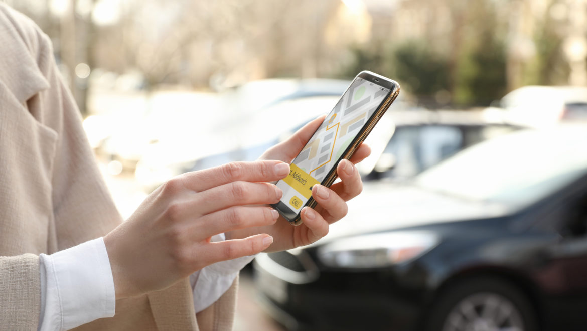 Woman ordering taxi with smartphone on city street, closeup